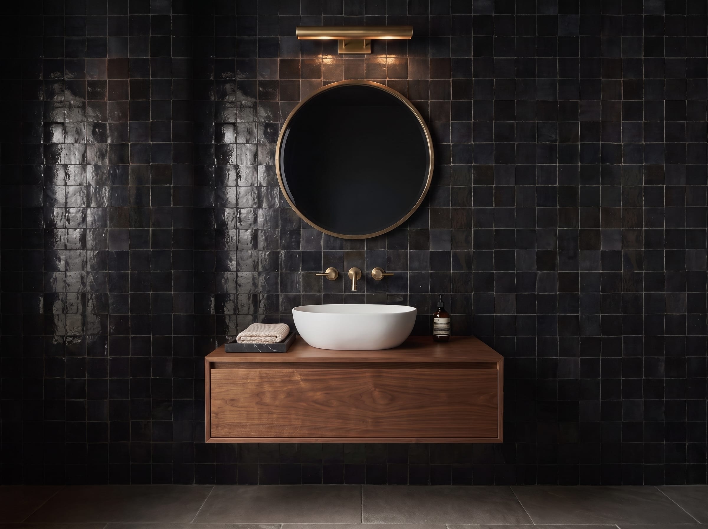 Black Zellige-style tile bathroom with a floating walnut vanity, brushed brass mirror, picture light and white vessel basin