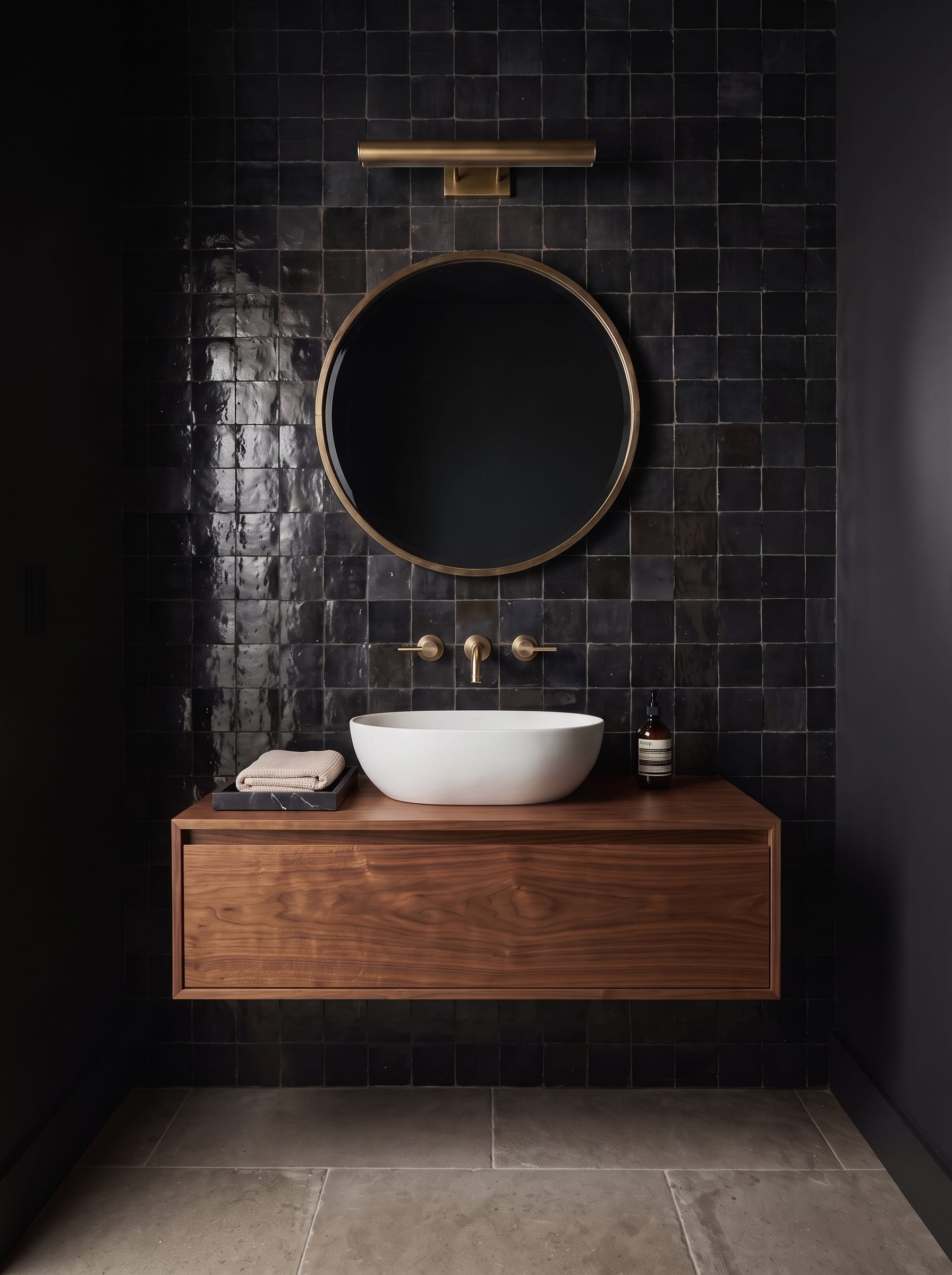 Black Zellige-style tile bathroom with a floating walnut vanity and white vessel sink shown in bright daylight and warm evening lighting.