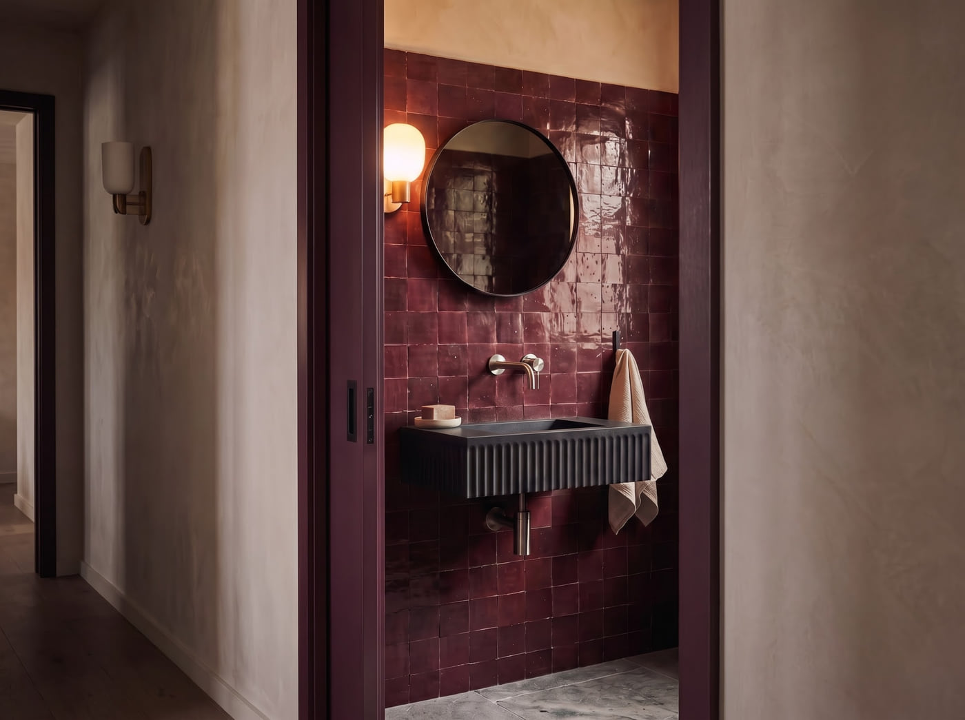 Compact powder room design study featuring glossy maroon tile walls and a wall-mounted matte black fluted basin.