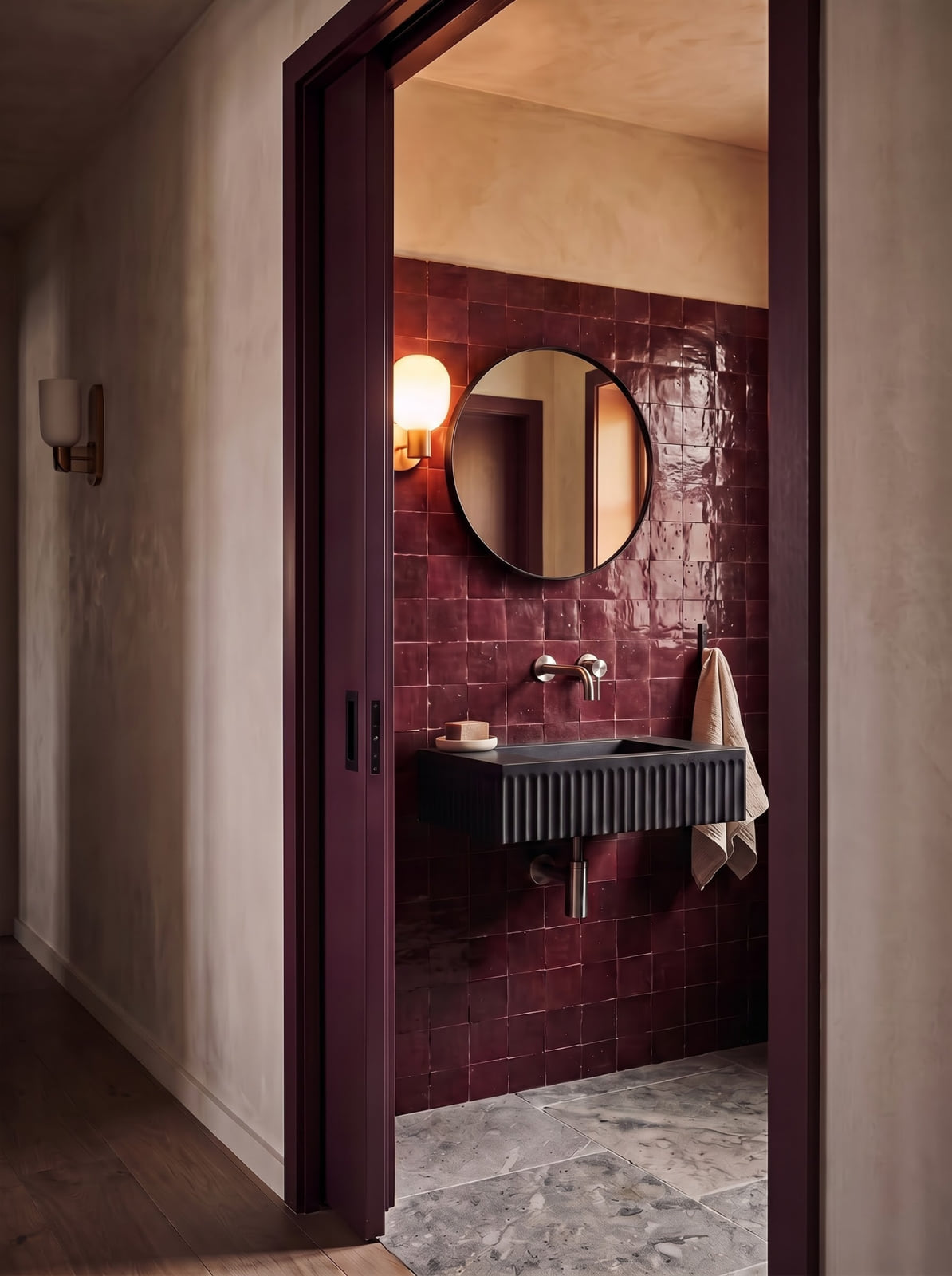 Burgundy tile powder room shown under soft natural daylight and warm evening sconce light.