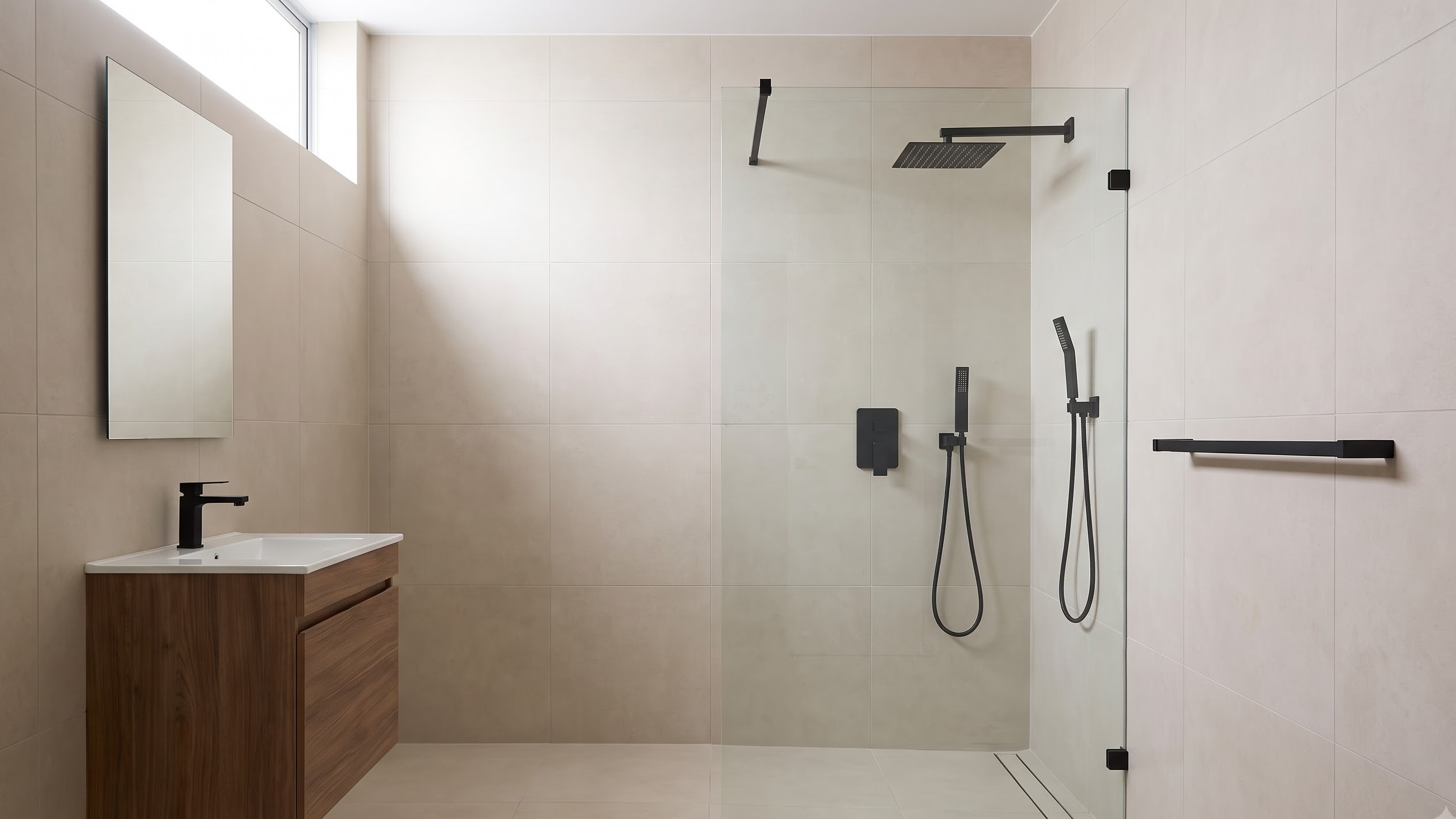 Spacious walk-in shower with matte-black fixtures and wood floating vanity