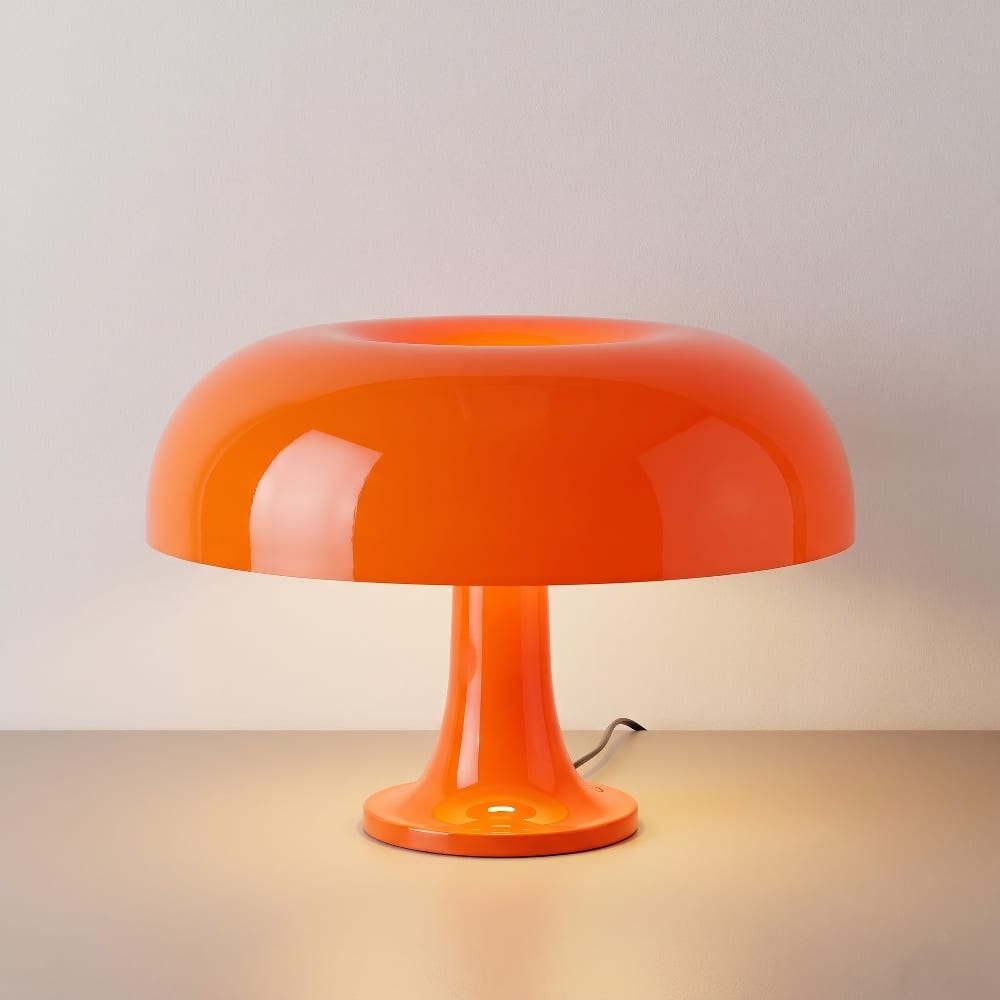 Glossy orange glass mushroom table lamp with a domed shade on a light surface