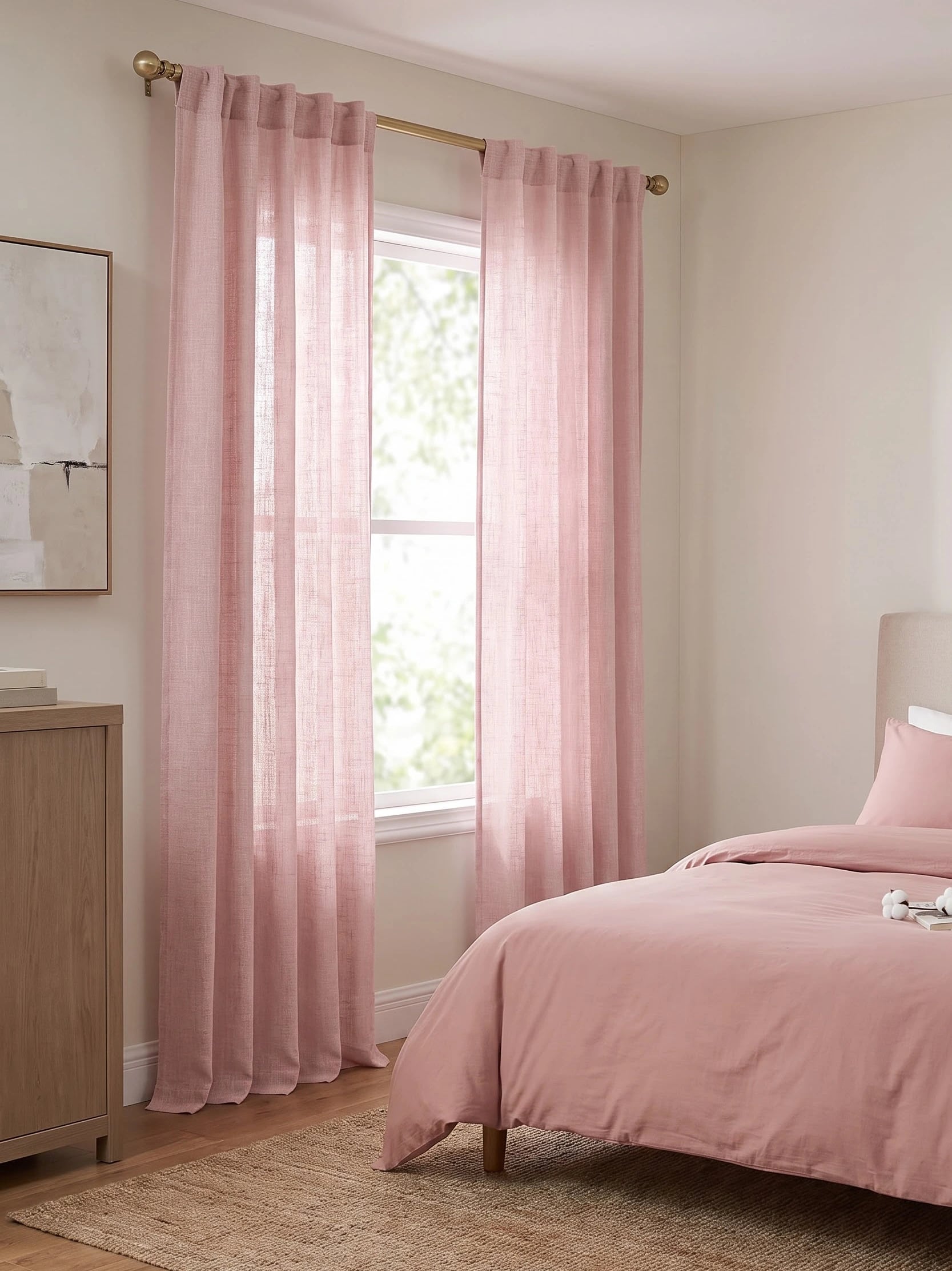 Soft pink curtains diffusing daylight beside a tranquil bedroom bed with neutral walls