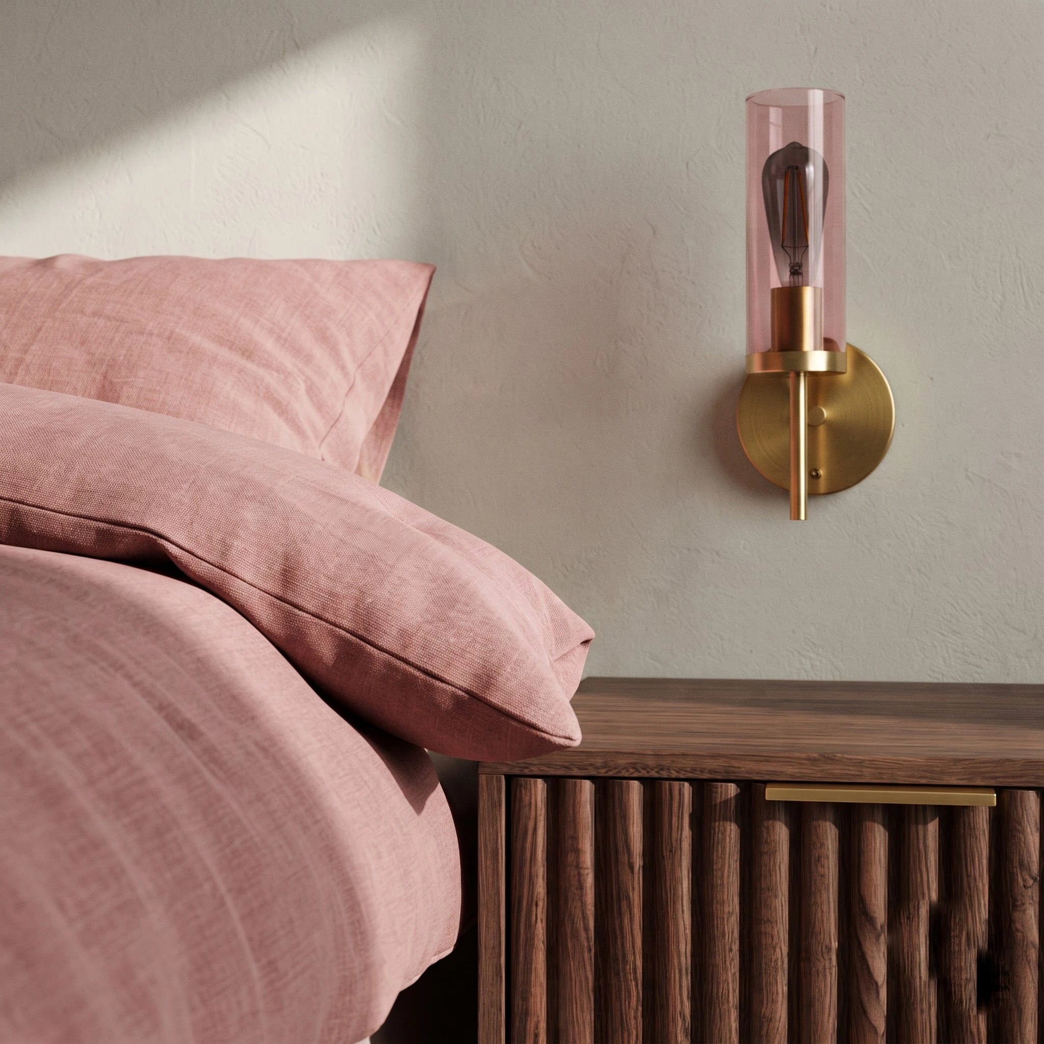 Close-up detail of fluted pink glass and brushed metal bedside wall light fitting