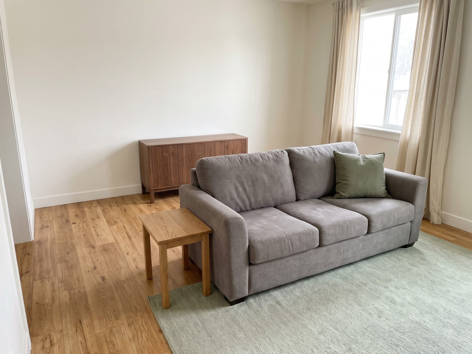 Warm wood and a pale green rug can change the atmosphere without replacing the main seating.