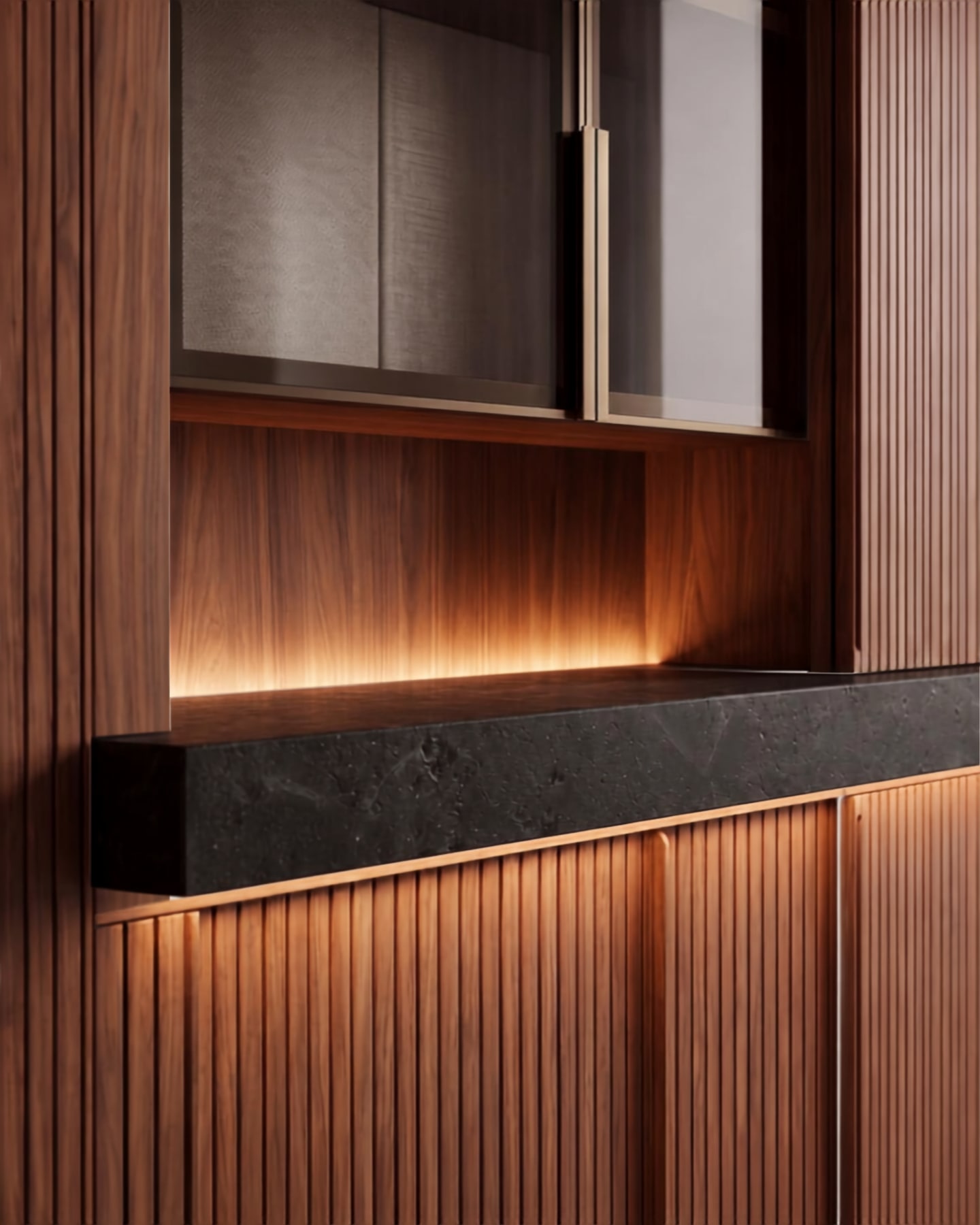 Fluted walnut cabinetry with integrated cove lighting accenting a dark stone countertop and upper glass cupboard.