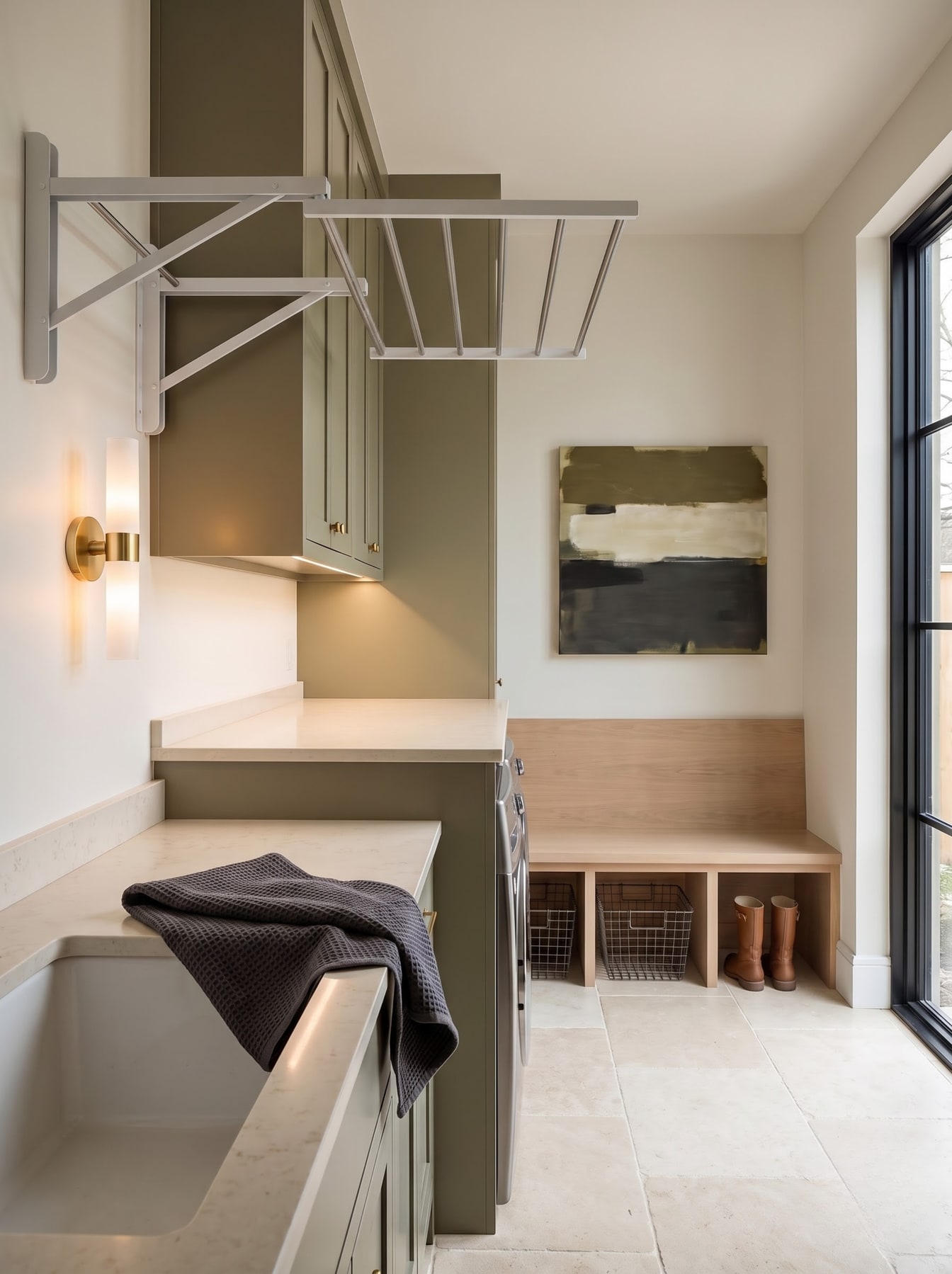 Laundry room corner featuring an olive-green cabinet, wall-mounted folding drying rail, stone countertop, and low wooden storage bench.