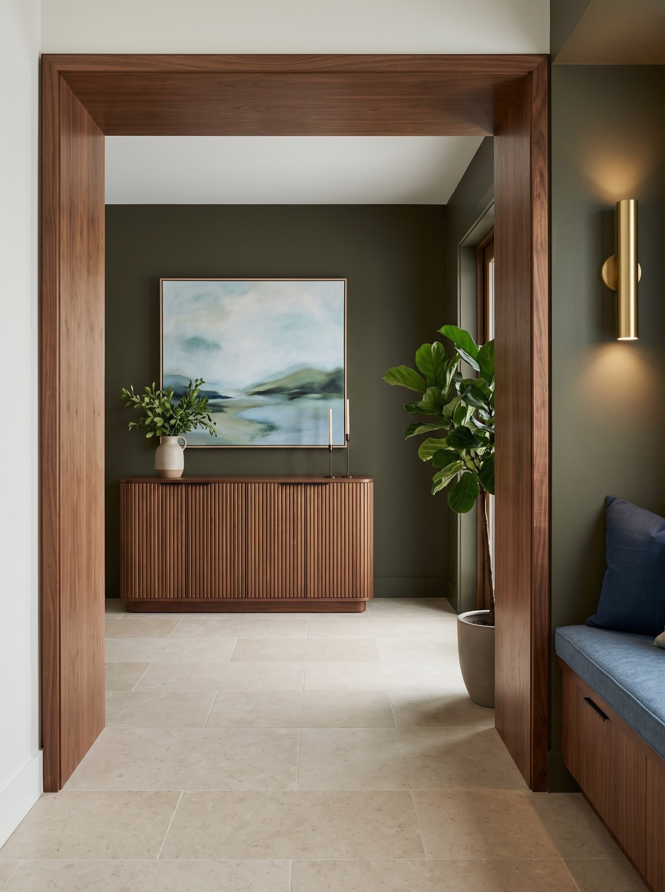 Rich walnut cased opening framing an olive-green room with a fluted wooden credenza, landscape painting, and indoor plant.